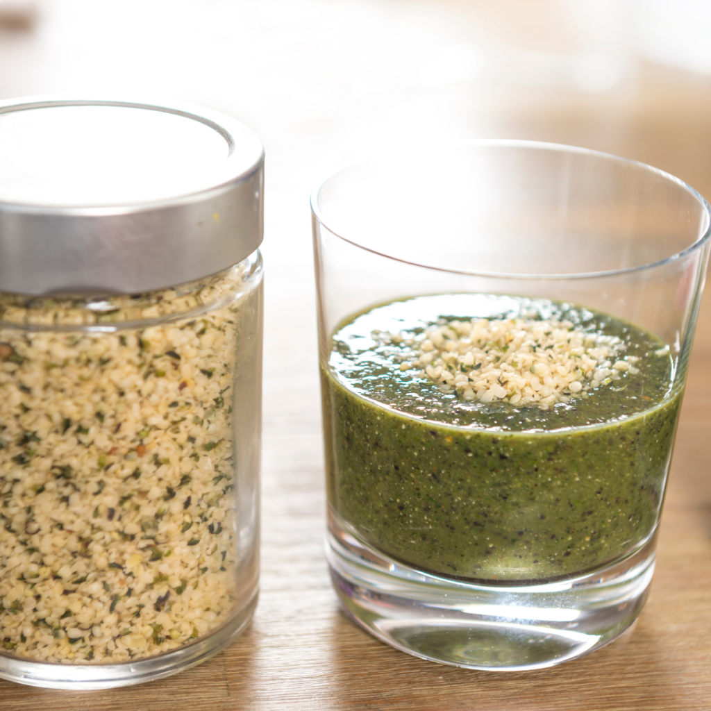 Green smoothie topped with hemp seeds with a jar full of them to the side
